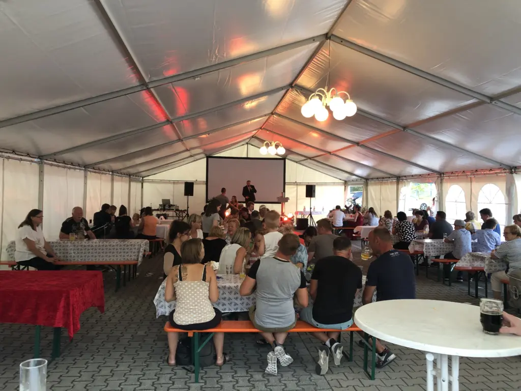 Dj und Technik bei einer Firmenveranstaltung in Pirna. Die Gäste sitzen und hören dem Roland Kaiser Double zu.